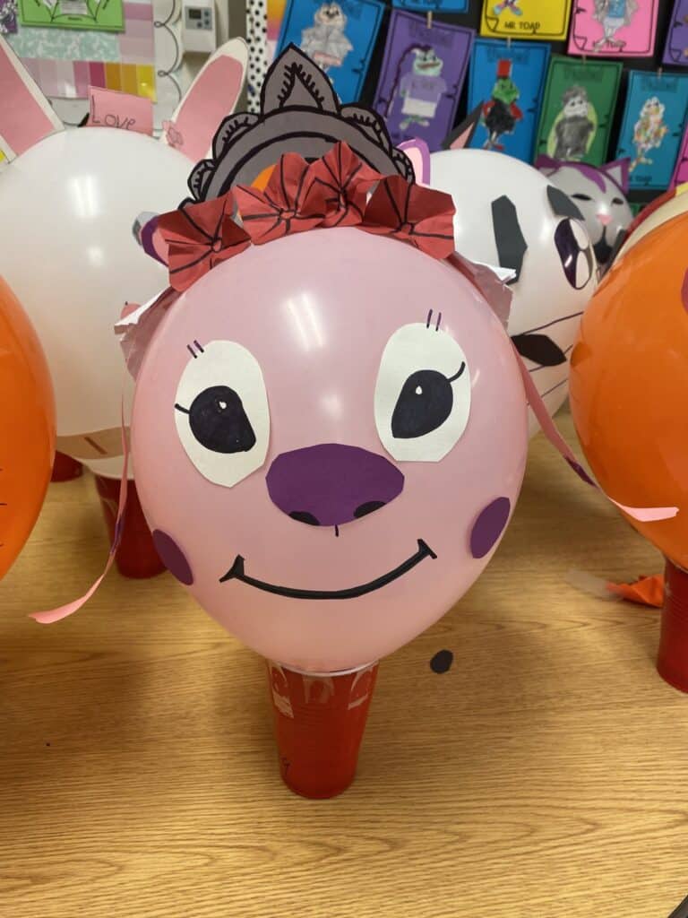 Student made pink parade balloon with a paper tiara and bows from a Balloons Over Broadway classroom workshop