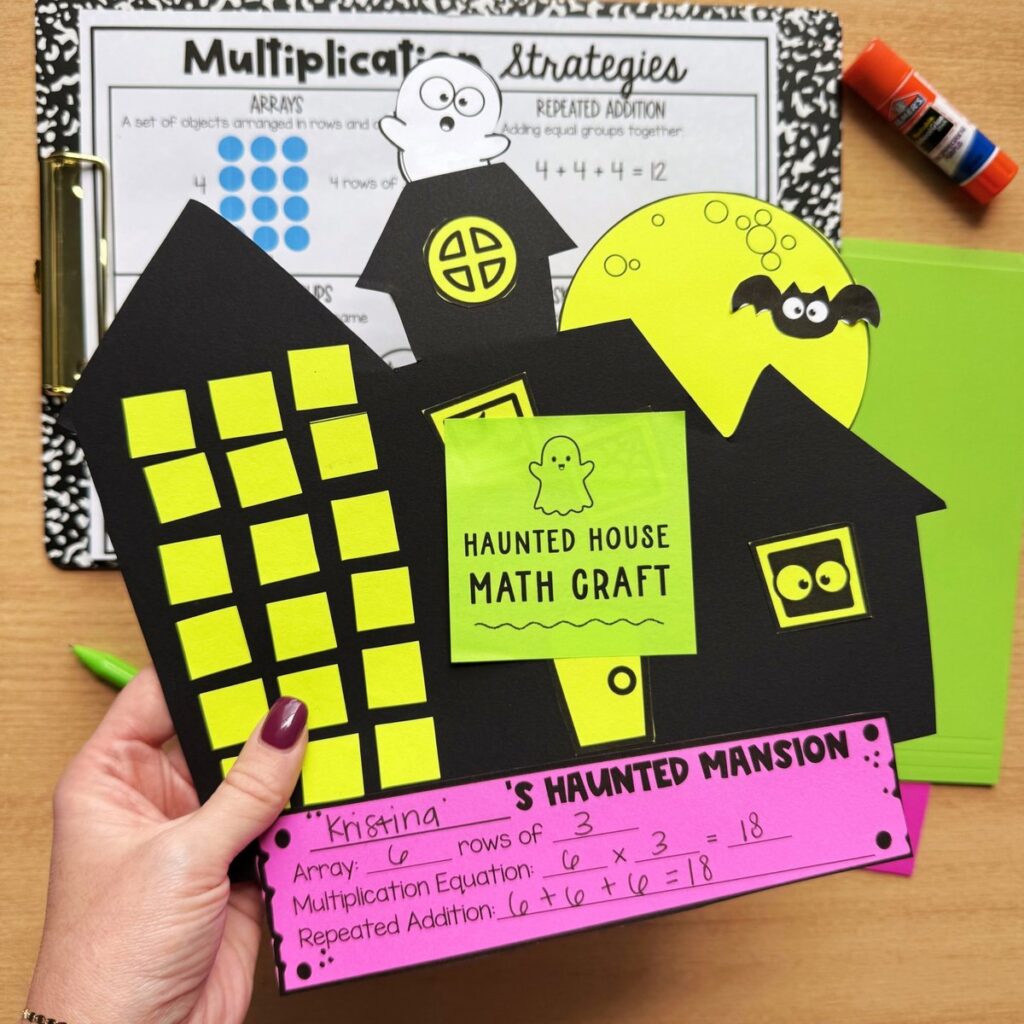 Haunted house math craft held up to show a 6 rows of 3 array with the multiplication equation 6 x 3 = 18 and repeated addition
